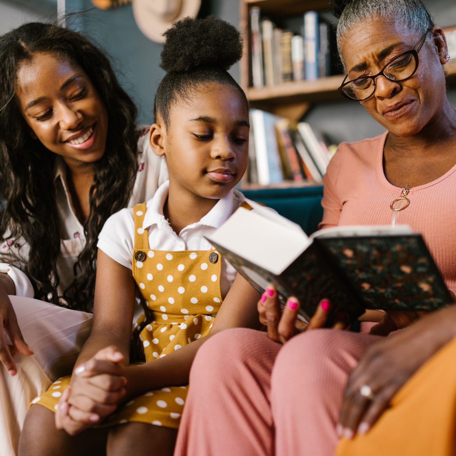 A grandmother reading a book with her daughter and granddaughter